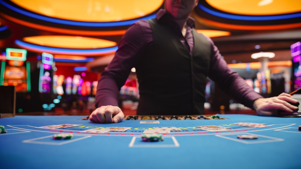 Dealer standing at table with chips and cards laid out.
