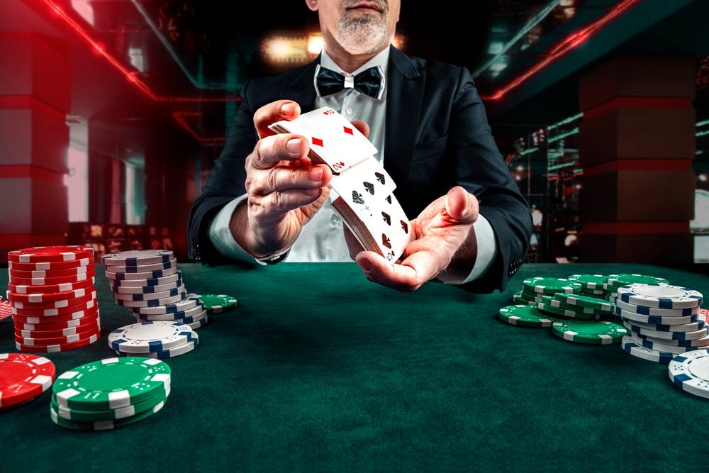 A dealer shuffleing cards with chips laid out to the side.