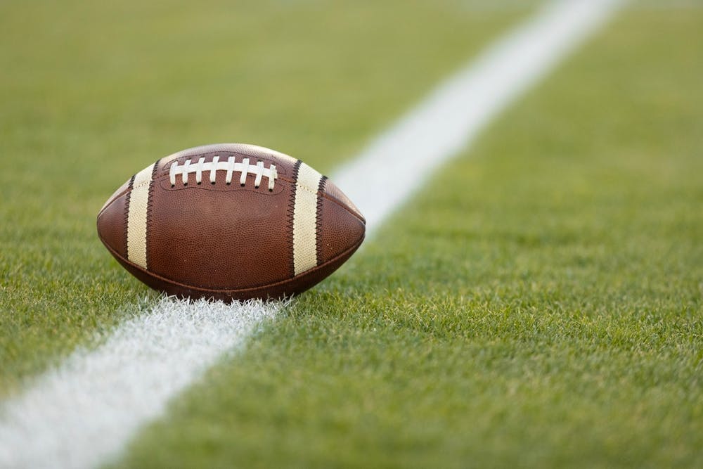 Football sitting on a yard line.