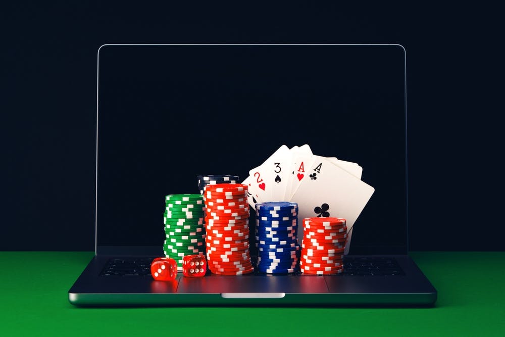 Online Casino play with cards chips, and dice laying on a keboard of a laptop. 