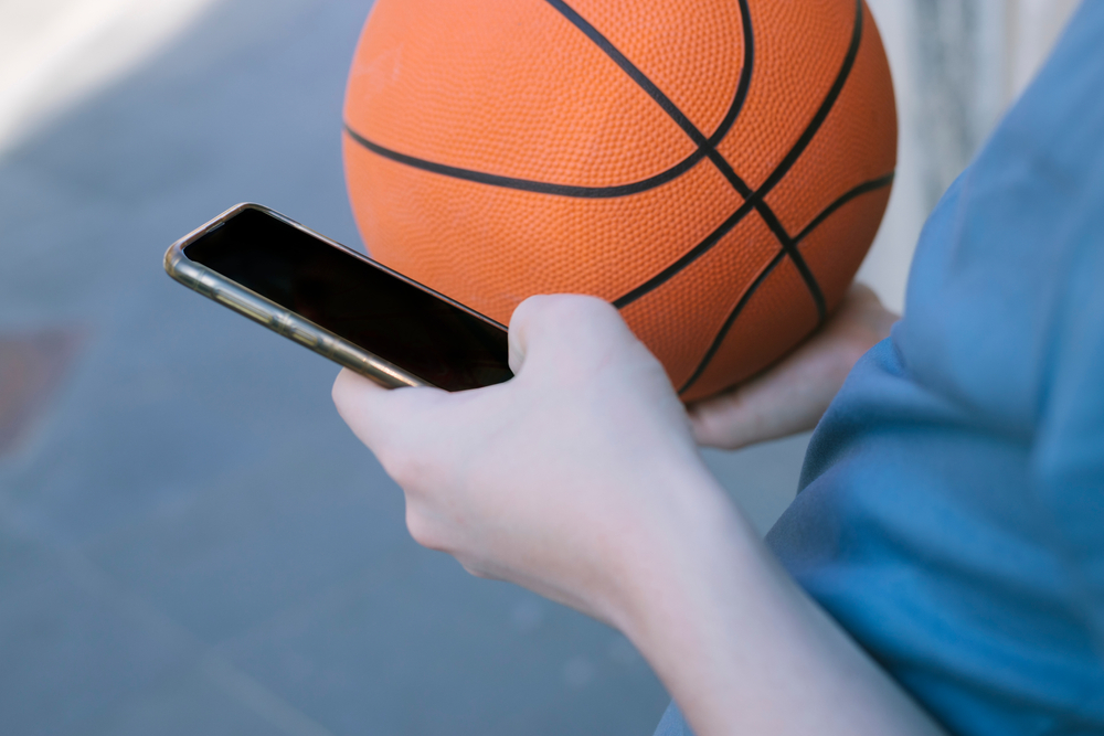 Someone placing a bet on basketball through their phone by betting online. 
