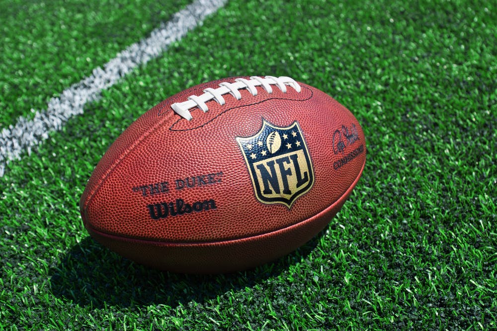 NFL ball placed on a football field near the yardline. 
