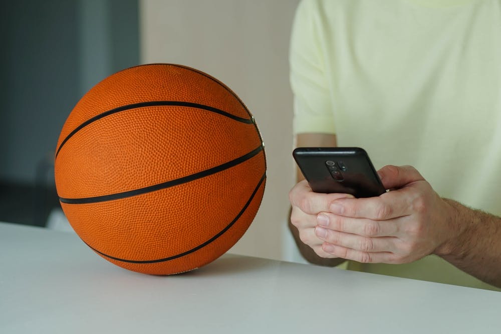 Someone placing a sports bet next to a basketball. 