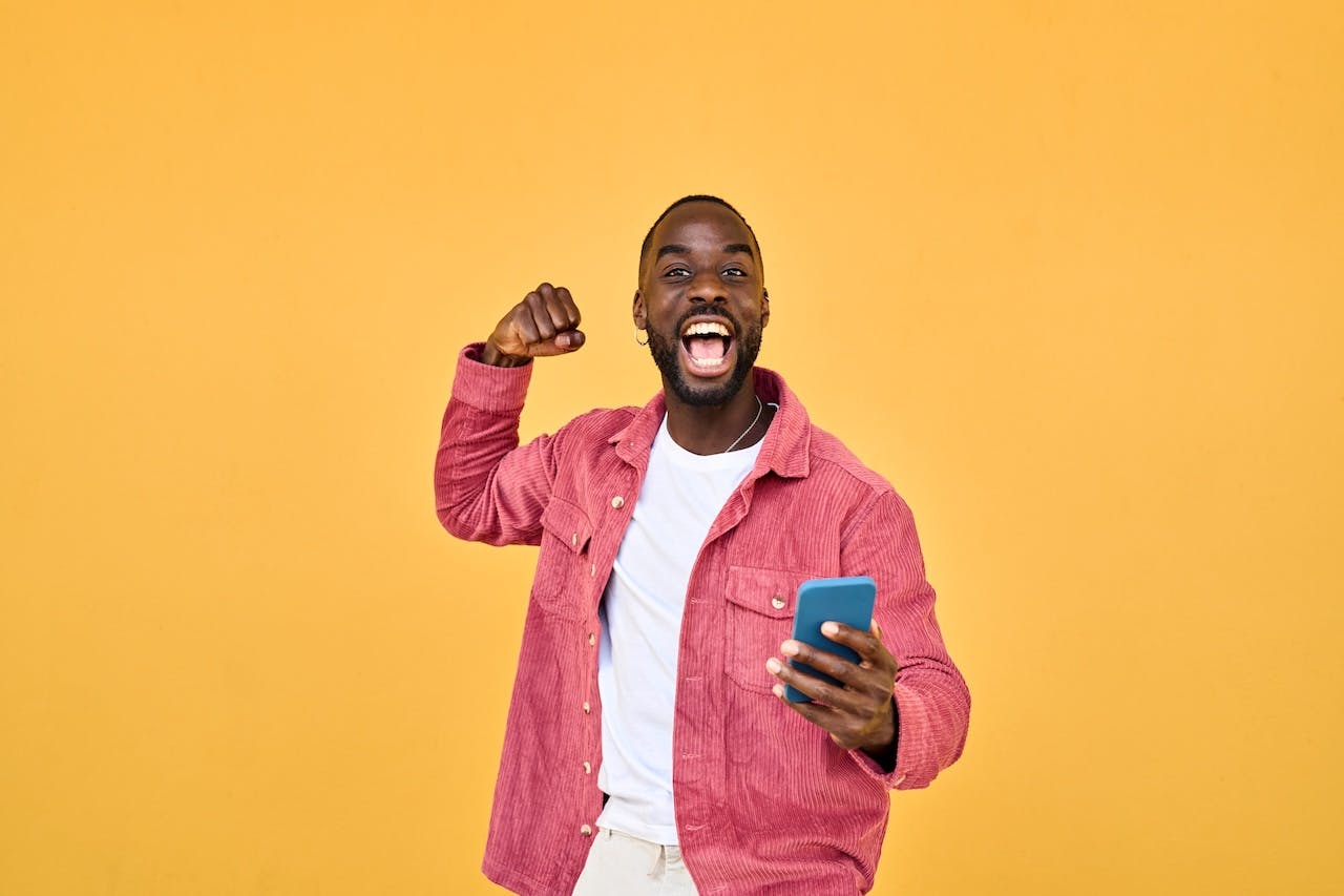 Man excited about sports betting while holding his phone. 