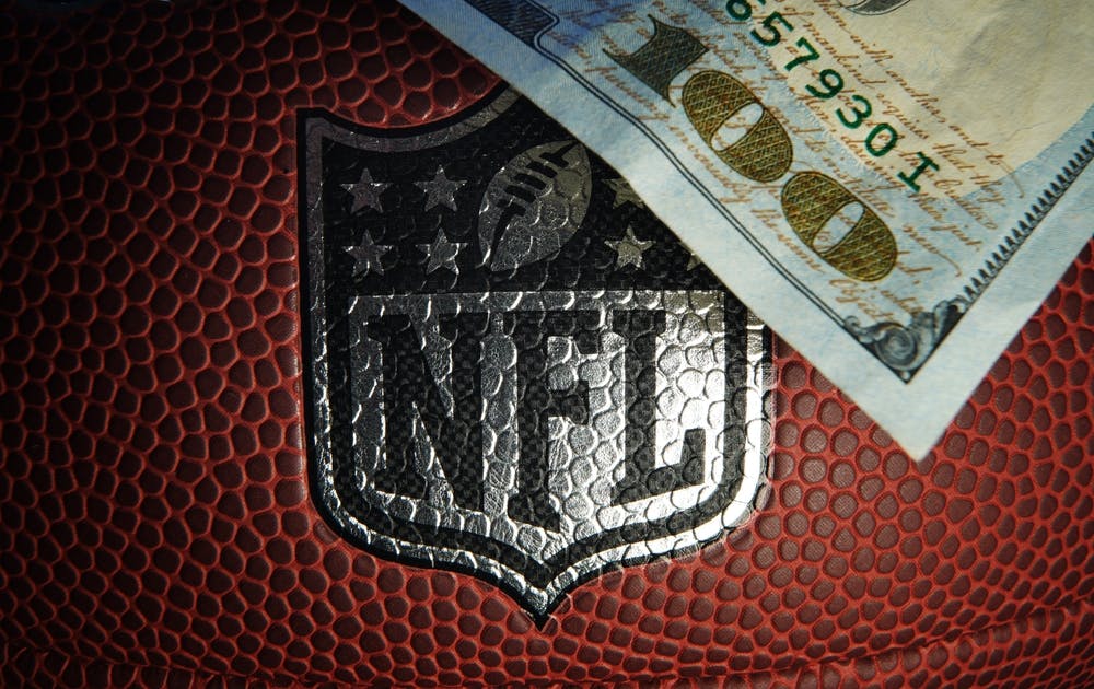 NFL football with an $100 bill laying on it. 