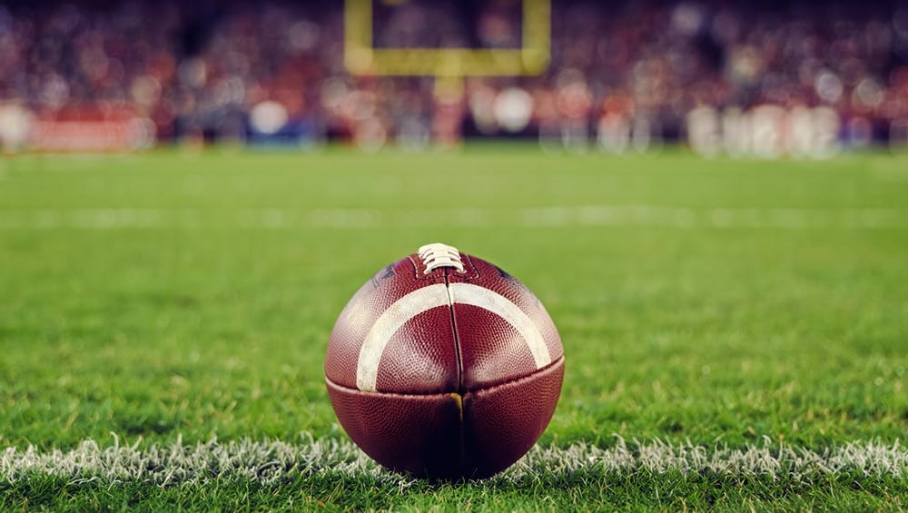 Football on a football field with the goal post in the background. 